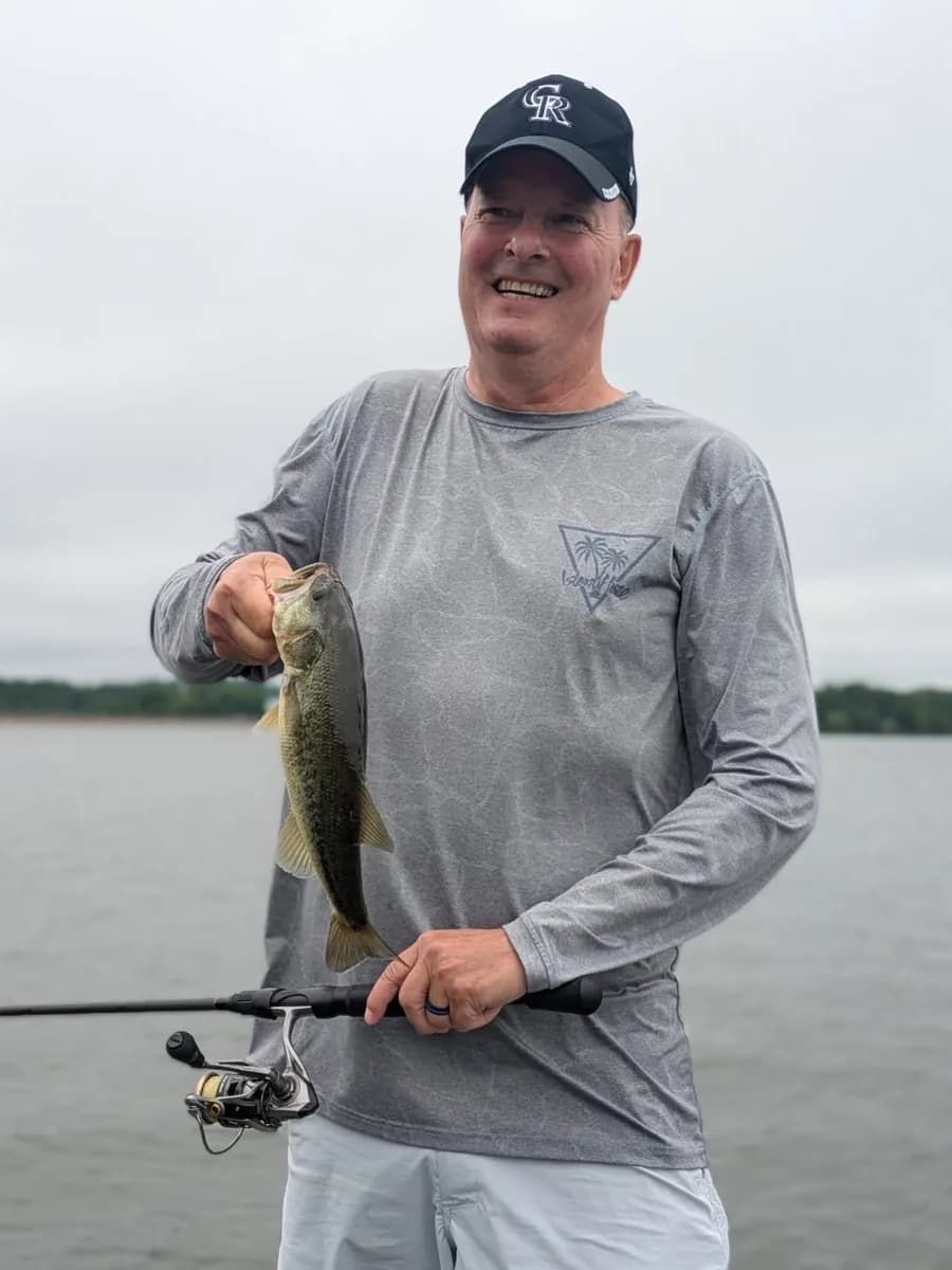 An angler on an overcast April morning with a largemouth bass