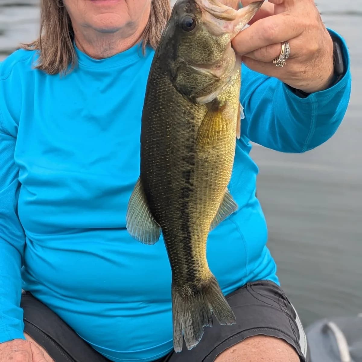 An angler holding up a heavy August largemouth bass