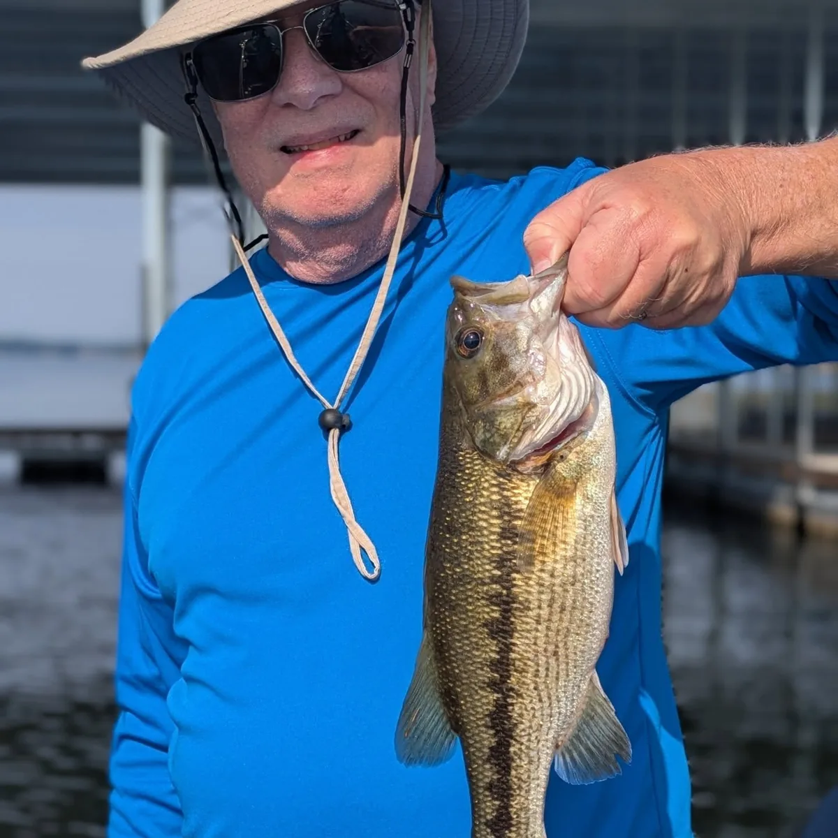 An angler in a sun hat with a largemouth bass