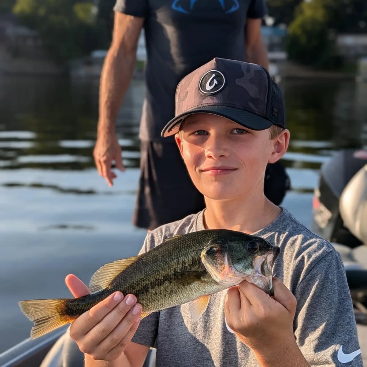 A young angler holding a largemouth bass with both hands
