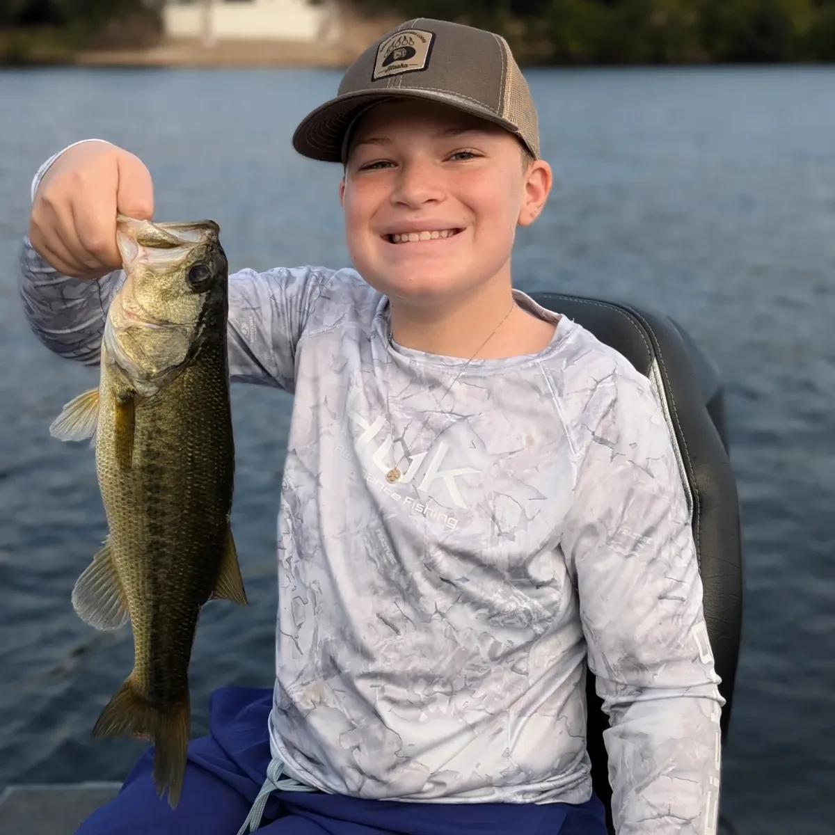 A young angler with a largemouth bass caught before the heat