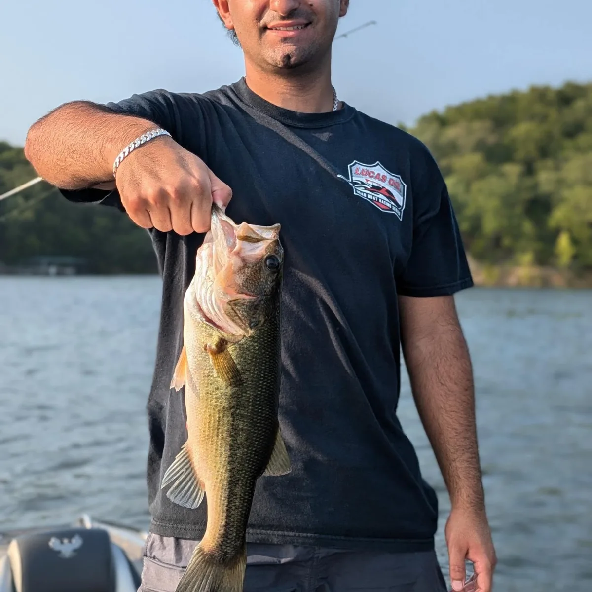 An angler holding a largemouth bass on an August evening