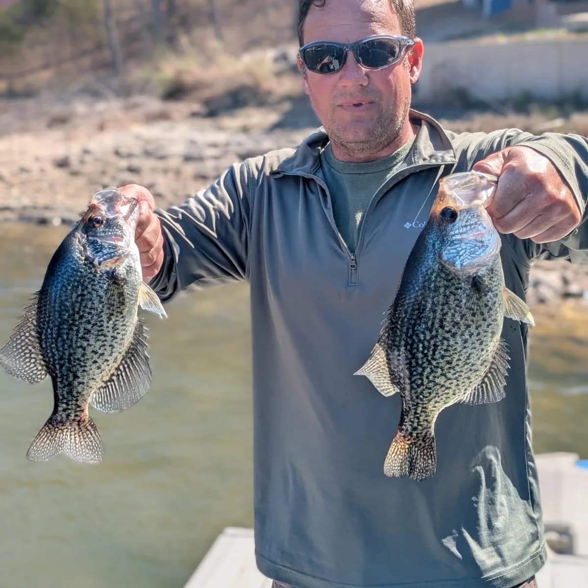 An angler holding a crappie in each hand on a February trip