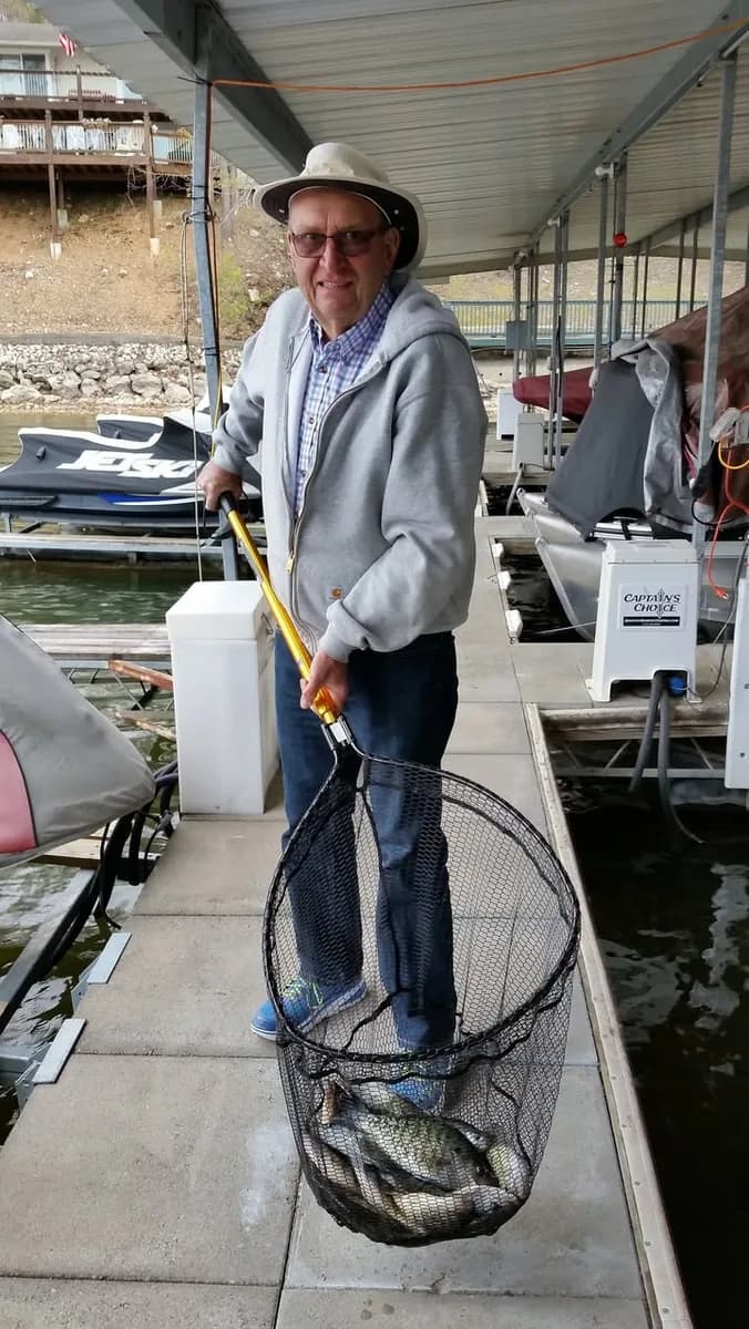 An angler lifting a net of crappie onto the dock