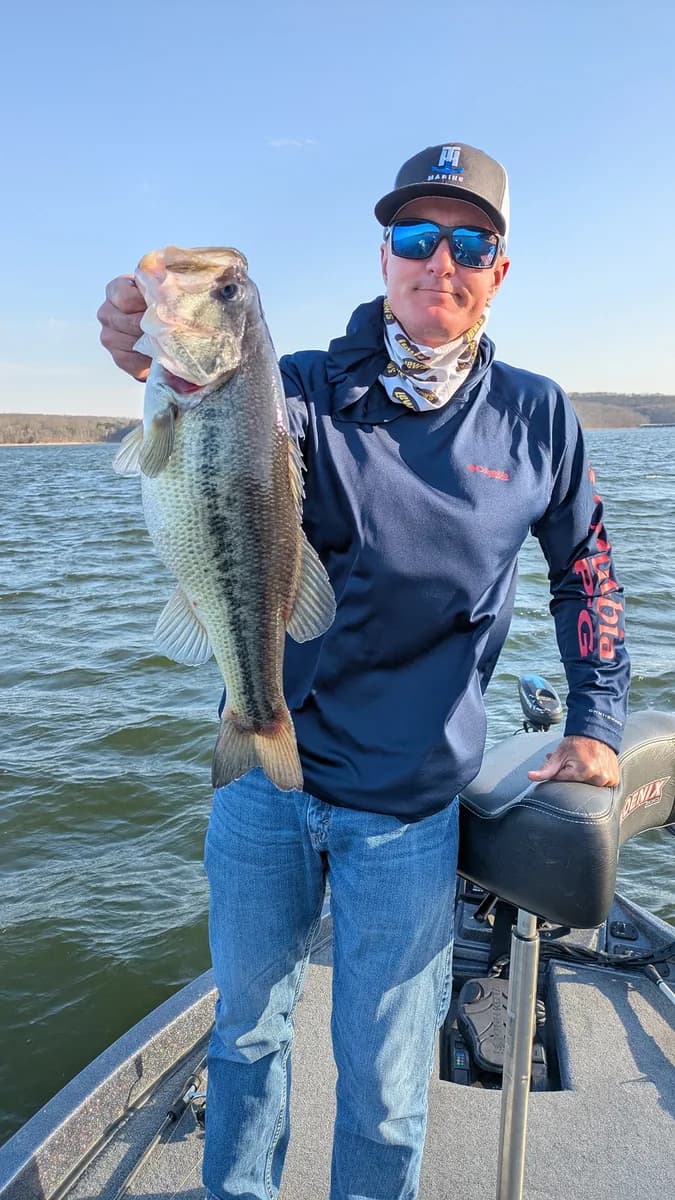 An angler in a hoodie with a crappie taken off winter brush