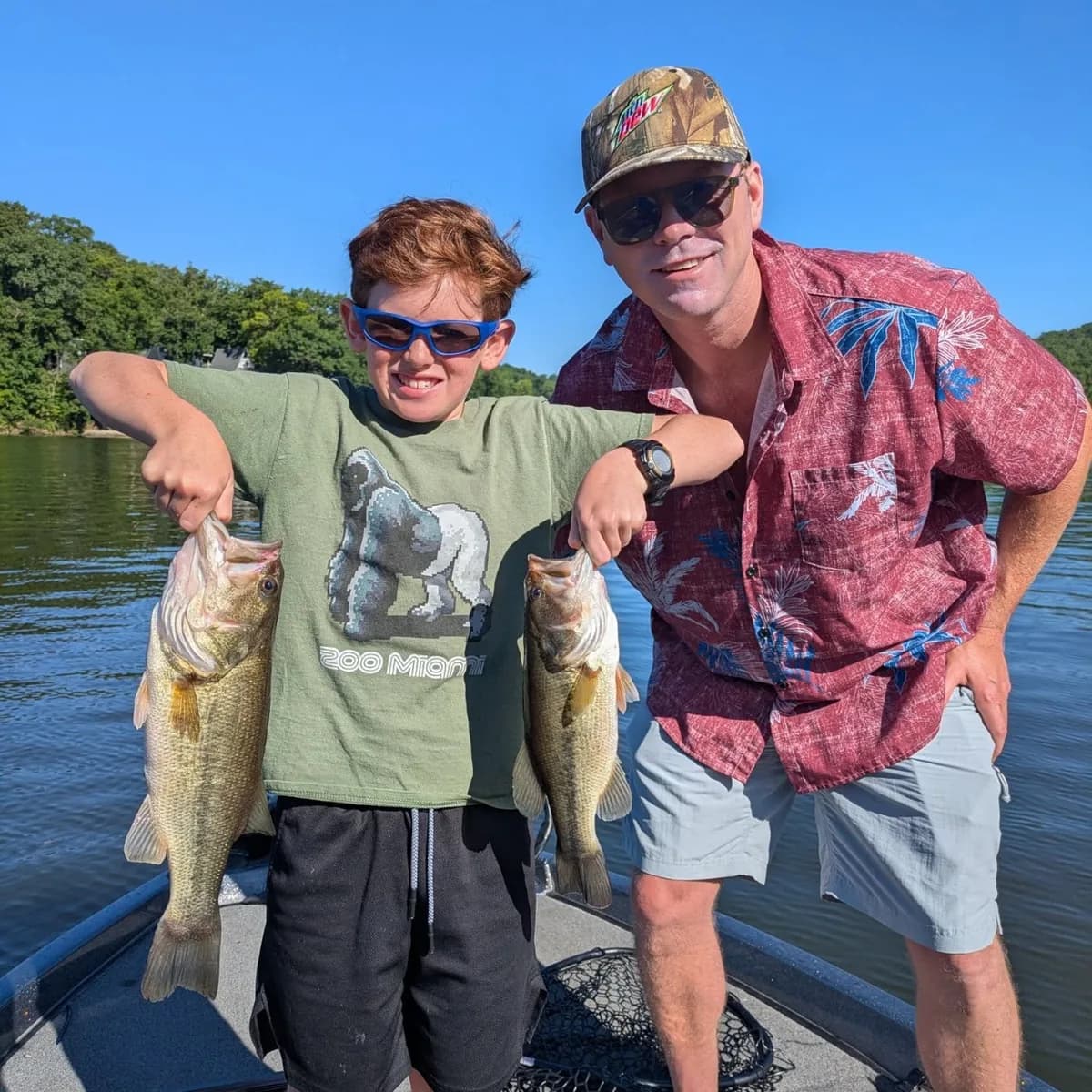 A young angler and an adult holding up two largemouth bass