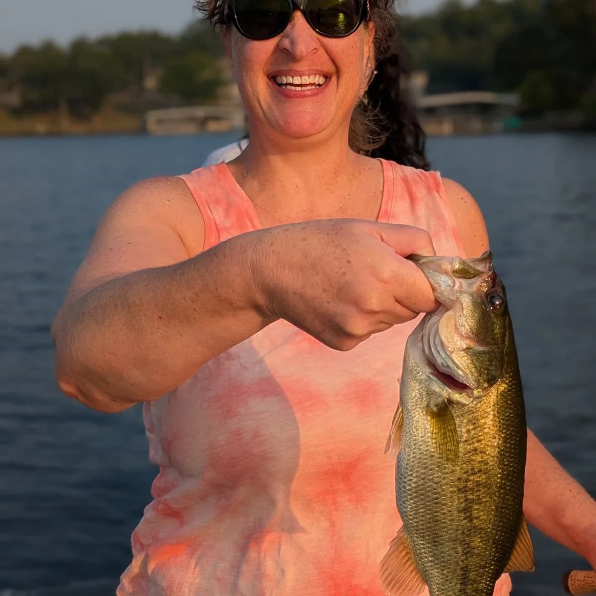 An angler holding a largemouth bass on a hot July morning