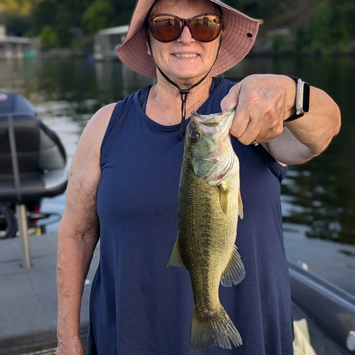 An angler in a sun hat holding a largemouth bass