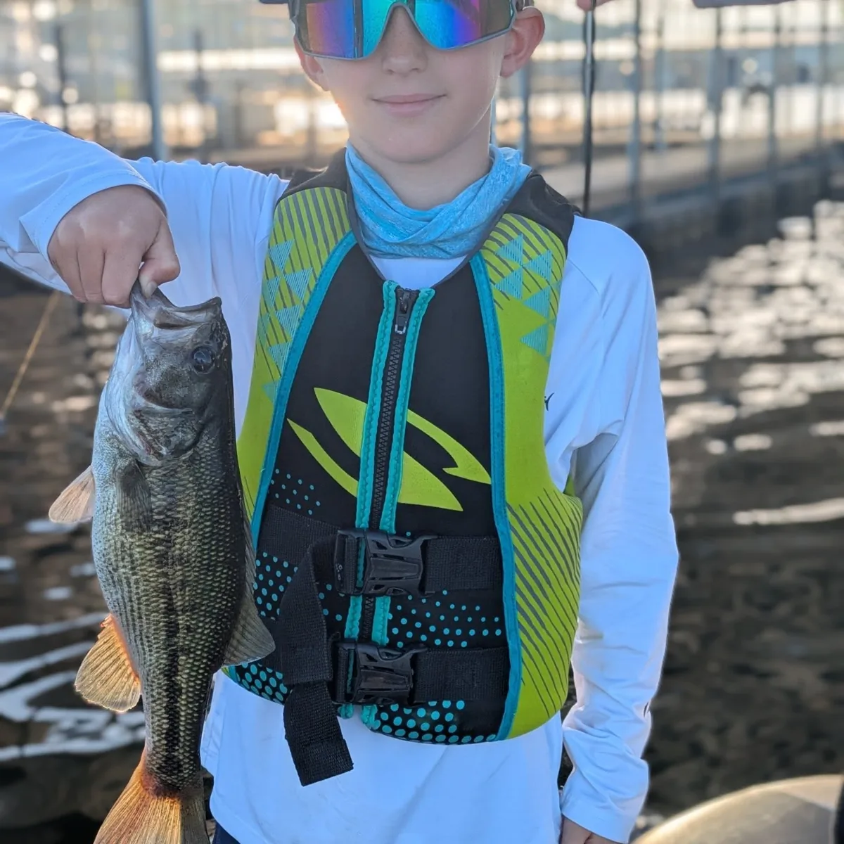 A young angler in a life jacket with a June largemouth bass