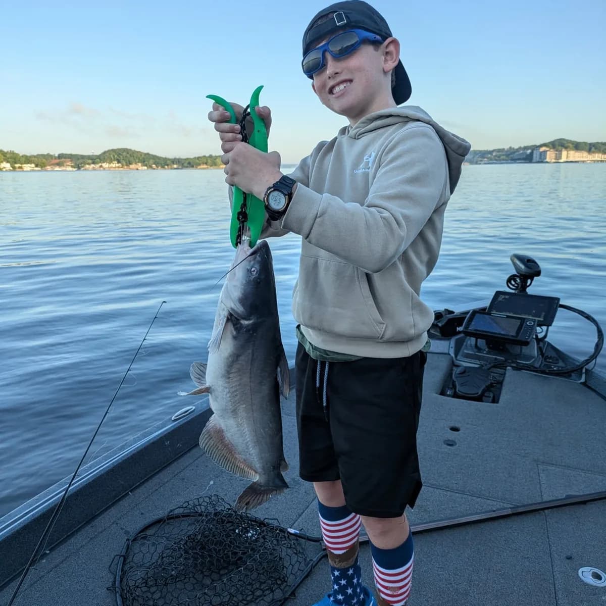 A young angler holding up a bass caught early in the morning