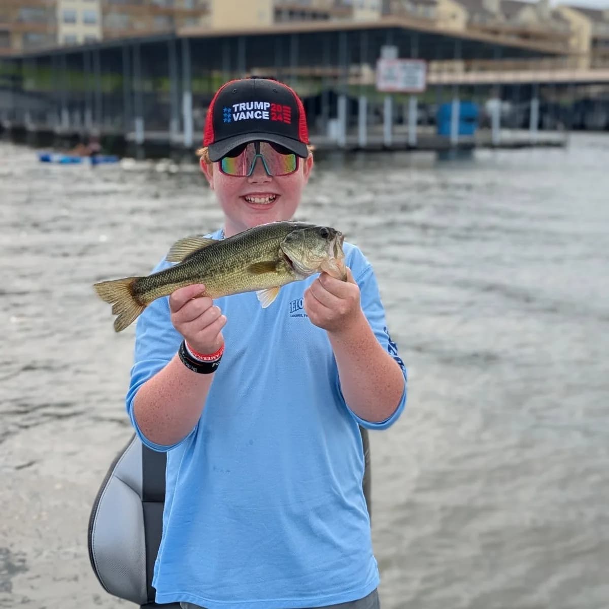 A young angler in a blue shirt holding a largemouth bass