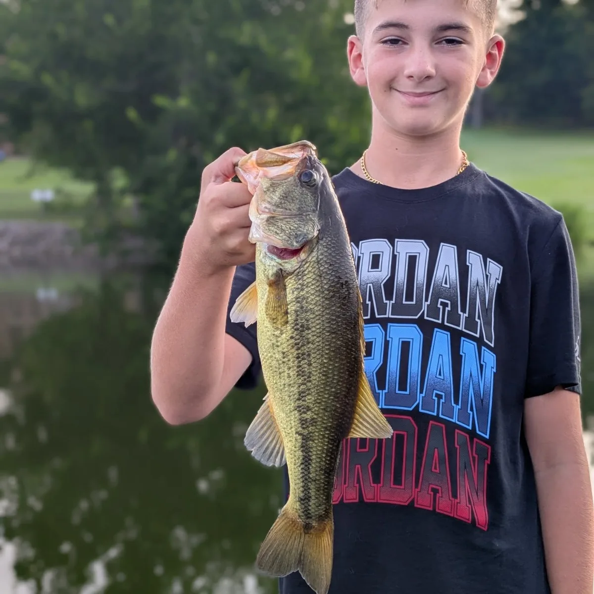 A teenage angler on the bow with a largemouth bass