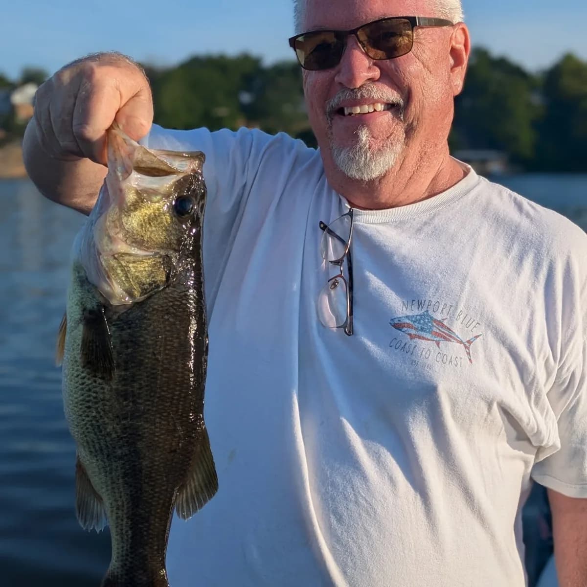 An angler in a white shirt with a June largemouth bass