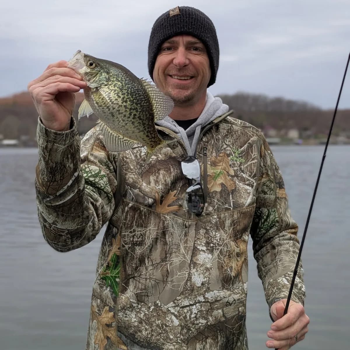 An angler in camo holding up a slab crappie