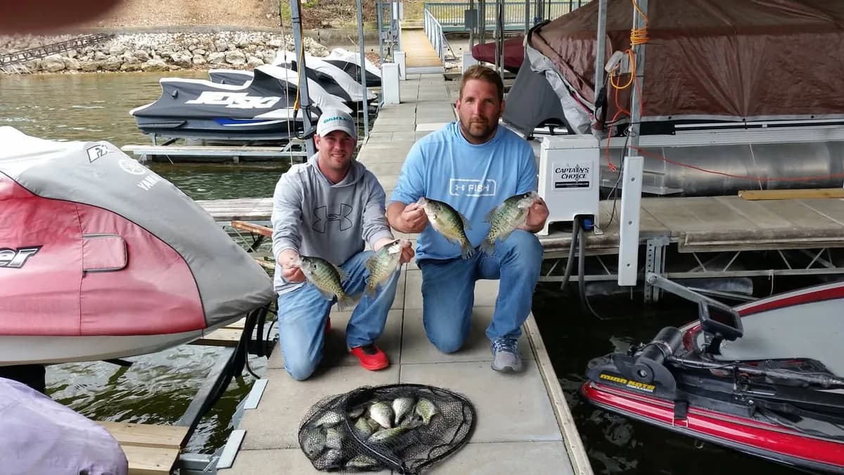 Two anglers kneeling on the dock with a morning's crappie