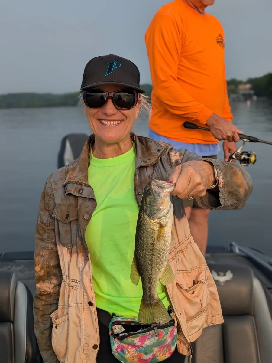 An angler holding a largemouth bass on an early May morning
