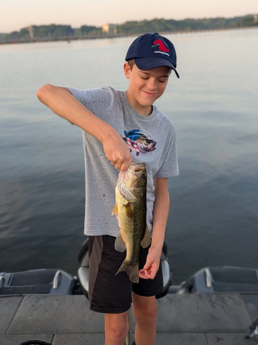 A young angler holding a largemouth bass caught in May