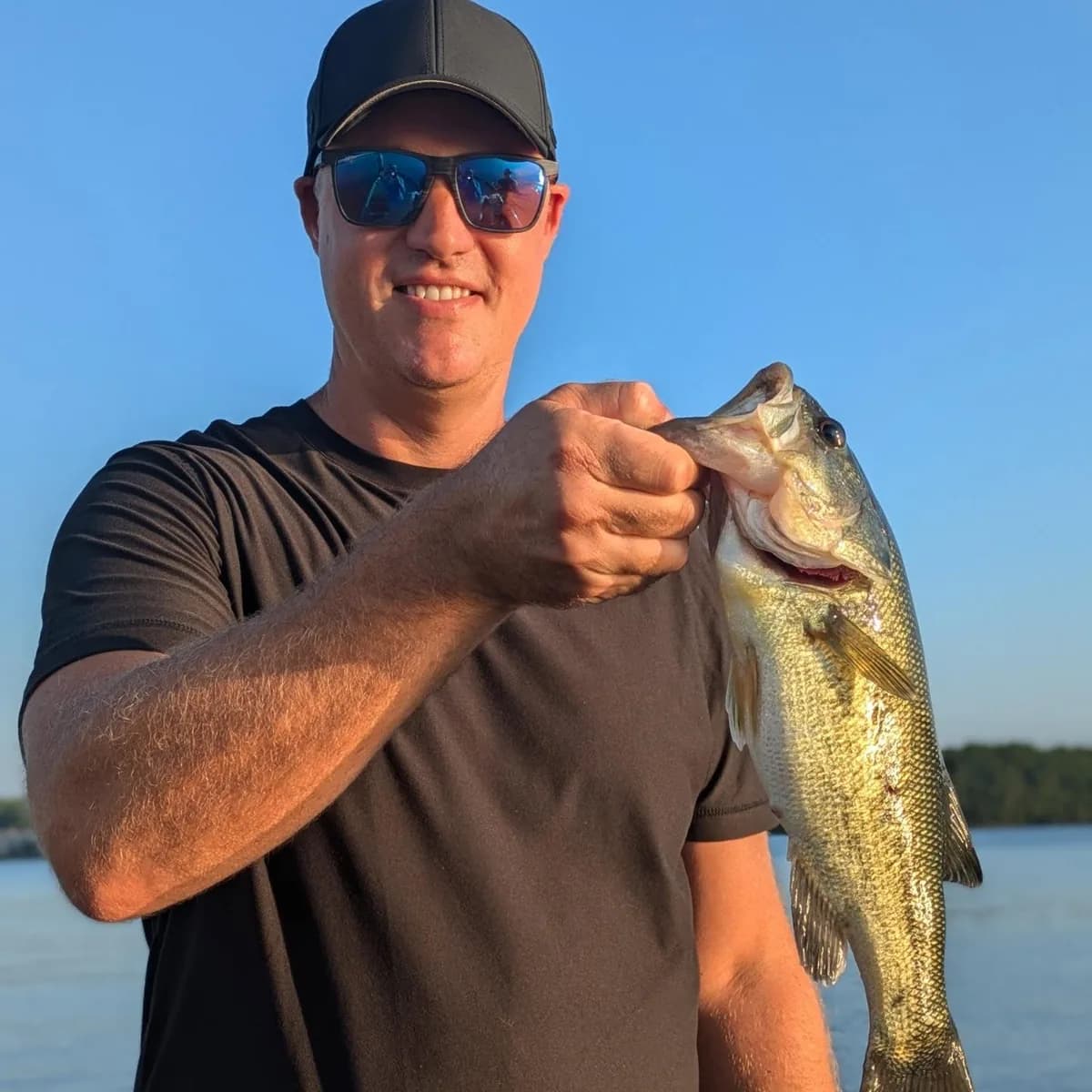 An angler in a cap and sunglasses with a September largemouth bass