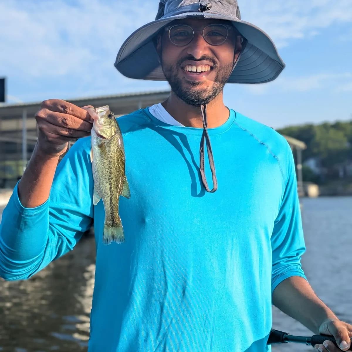 An angler in a sun hat holding a largemouth bass caught in September