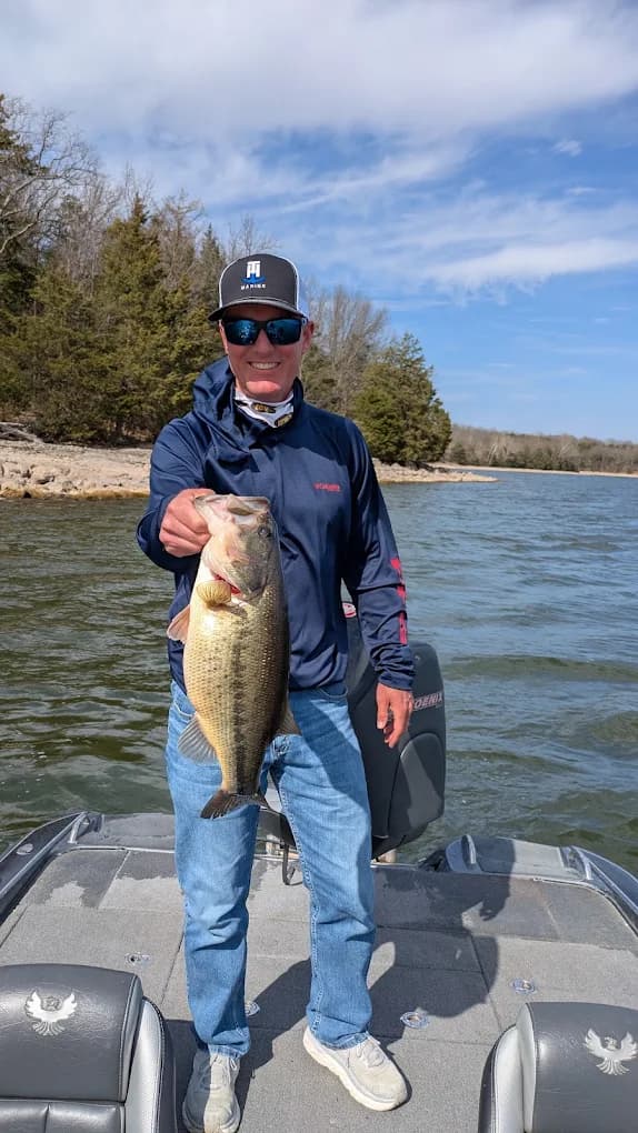 Captain Mike on the deck of his Phoenix bass boat with a largemouth bass on Lake of the Ozarks
